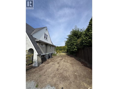A house with a grey roof and a dirt path leading to it.