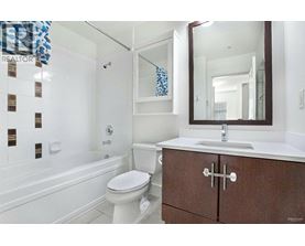 A white toilet sits in a bathroom next to a bathtub.