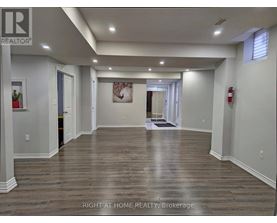 A spacious room with wooden flooring and white walls.