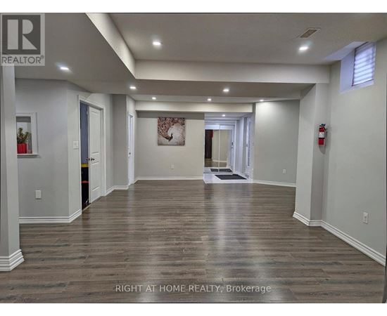 A spacious room with wooden flooring and white walls.