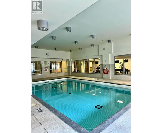 A swimming pool inside a building with a clock on the wall.