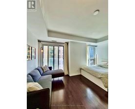 A bedroom with a bed, couch, and window.