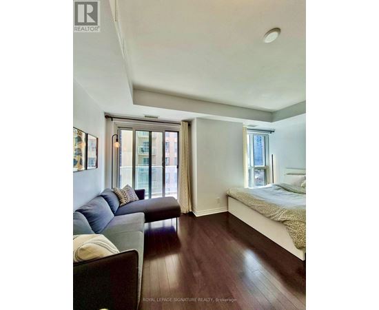 A bedroom with a bed, couch, and window.