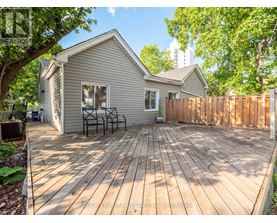 A wooden deck in front of a house with a fence and trees in the background.