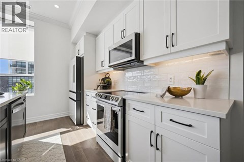 A modern kitchen with white cabinets and a black stove top.