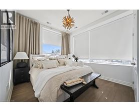 A bedroom with a large bed, a nightstand with a lamp, and a window with a view of trees.