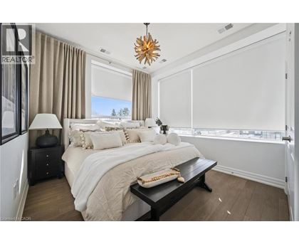 A bedroom with a large bed, a nightstand with a lamp, and a window with a view of trees.