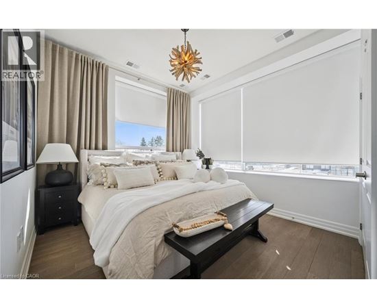 A bedroom with a large bed, a nightstand with a lamp, and a window with a view of trees.
