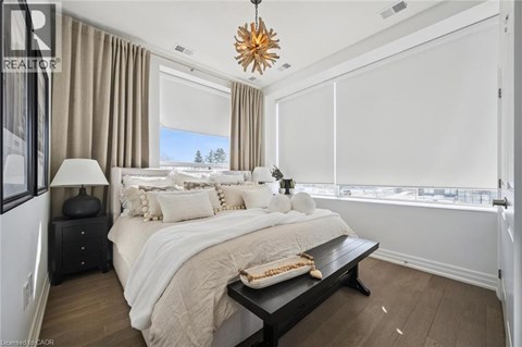 A bedroom with a large bed, a nightstand with a lamp, and a window with a view of trees.
