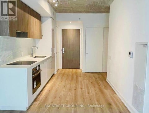A kitchen with wooden floors and white cabinets.