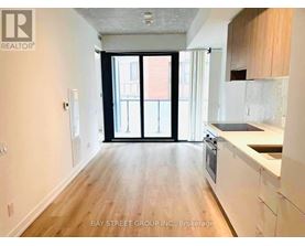 A spacious kitchen with white cabinets and a wooden floor.