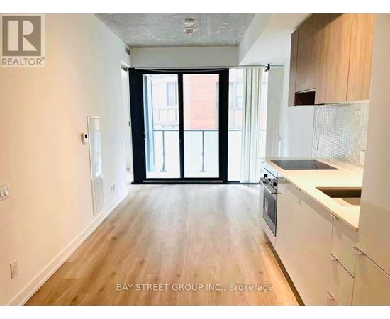 A spacious kitchen with white cabinets and a wooden floor.