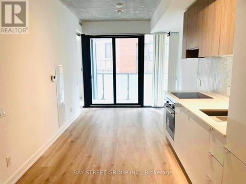 A spacious kitchen with white cabinets and a wooden floor.