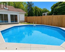 A blue pool in a backyard with a wooden fence.