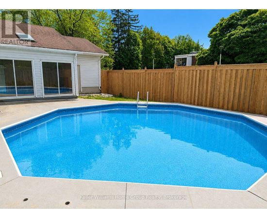 A blue pool in a backyard with a wooden fence.