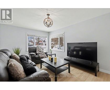A living room with a black leather couch and a flat screen TV.