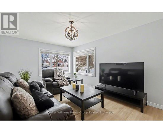 A living room with a black leather couch and a flat screen TV.