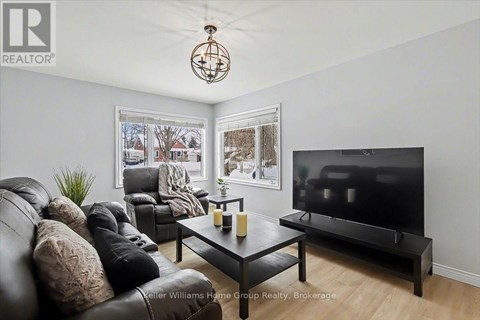 A living room with a black leather couch and a flat screen TV.