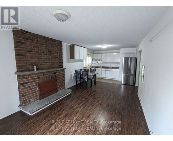A room with a brick fireplace and wooden floors.