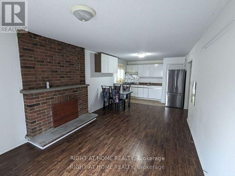 A room with a brick fireplace and wooden floors.
