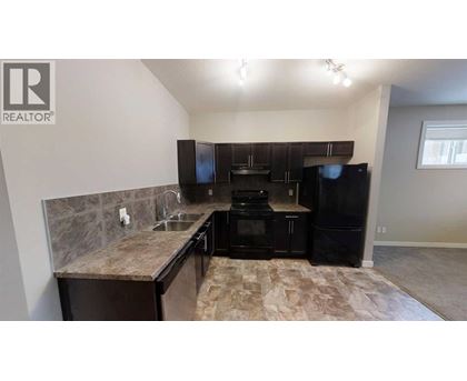 A kitchen with black appliances and a marble countertop.