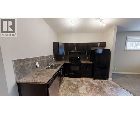 A kitchen with black appliances and a marble countertop.