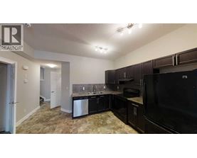 A kitchen with black appliances and brown cabinets.