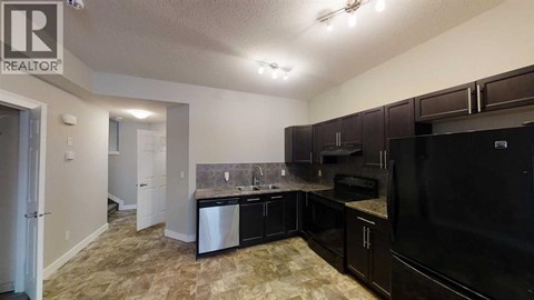 A kitchen with black appliances and brown cabinets.