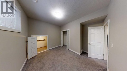 A realtor sign is on the wall of a sparsely furnished room.