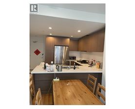 A kitchen with wooden chairs and a stainless steel refrigerator.
