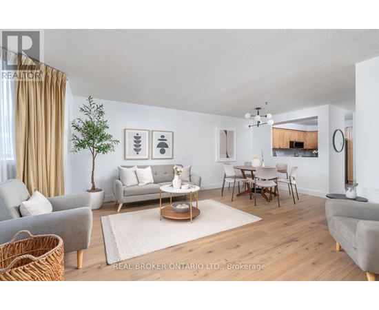 A well-lit living room with a grey sofa, a wooden coffee table, and a dining table with chairs.