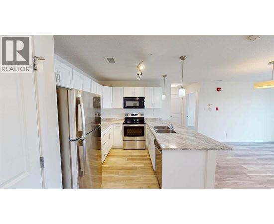 A kitchen with a refrigerator, stove, and sink.