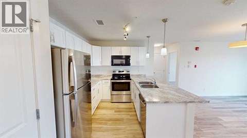 A kitchen with a refrigerator, stove, and sink.