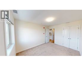 A white bedroom with a window and a door leading to another room.