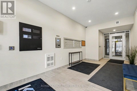 A well-lit, spacious living room with a flat-screen TV, a whiteboard, and a glass door leading to another room.