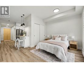 A bedroom with a large bed and a kitchenette area.