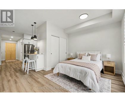 A bedroom with a large bed and a kitchenette area.