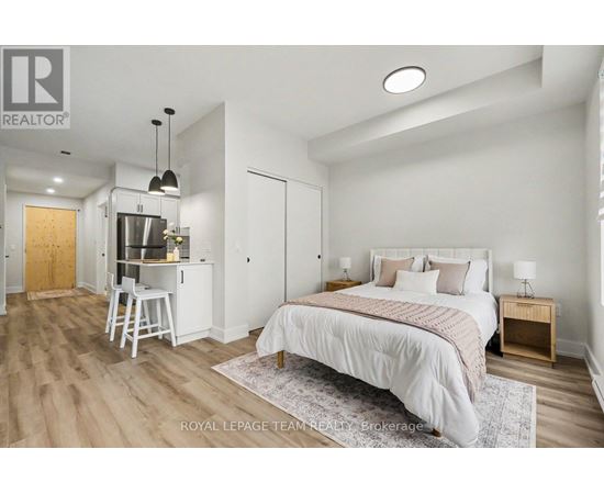 A bedroom with a large bed and a kitchenette area.