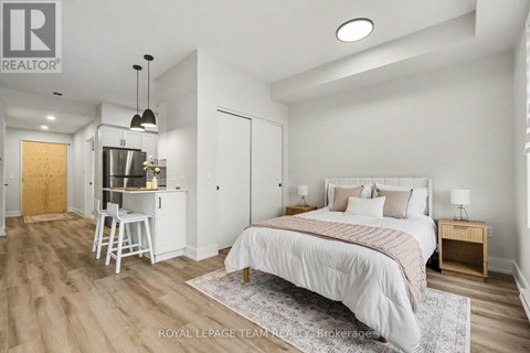 A bedroom with a large bed and a kitchenette area.