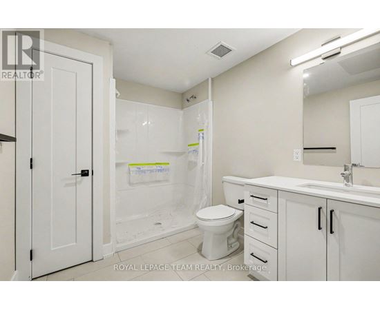 A white bathroom with a toilet, sink, and shower.