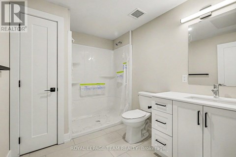 A white bathroom with a toilet, sink, and shower.
