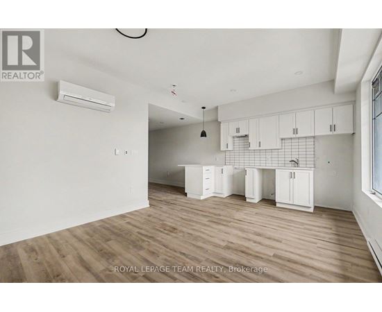 A spacious room with wooden flooring and white walls.