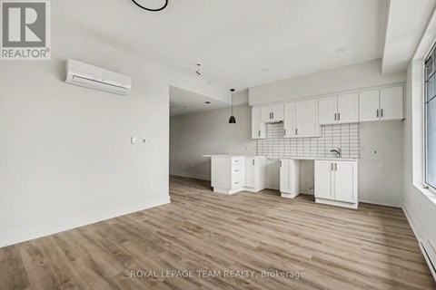 A spacious room with wooden flooring and white walls.