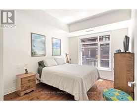 A bedroom with a bed, nightstand, and window.