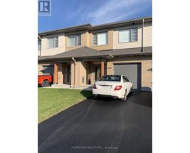 A white car is parked in front of a two-story house.