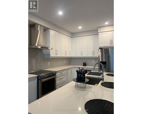 A modern kitchen with white cabinets and stainless steel appliances.