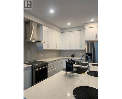 A modern kitchen with white cabinets and stainless steel appliances.