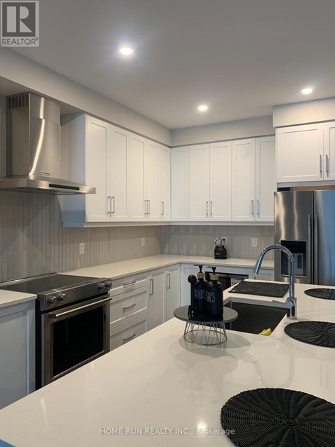 A modern kitchen with white cabinets and stainless steel appliances.