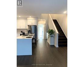 A modern kitchen with a stainless steel refrigerator and a wooden floor.