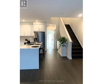 A modern kitchen with a stainless steel refrigerator and a wooden floor.